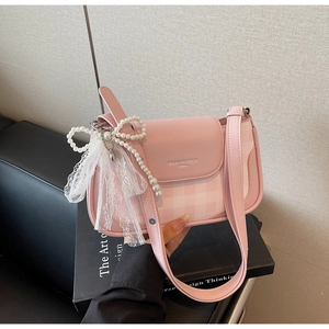 Close-up of pink leather handbag featuring pearl bow charms and delicate lace details