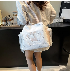 Detailed side view of white polka dot tote bag with bunny embroidery and lace edge