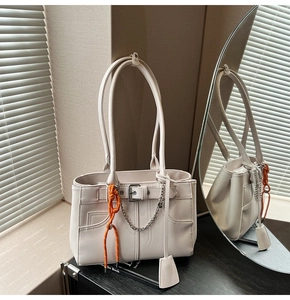 Détail du sac cabas en similicuir crème avec chaîne en métal et breloque orange