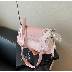 Detailed shot of pink plaid underarm bag featuring a pearl and lace bow charm accessory