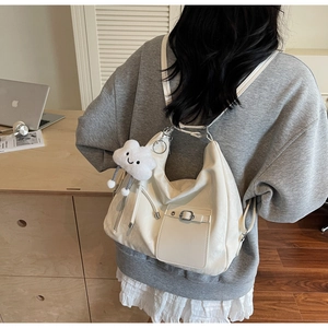 Detail of white PU leather tote bag with cloud plush charm and functional side pocket