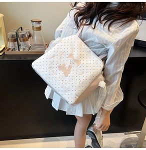 Close-up of white polka dot backpack featuring Moon Shark embroidery and lace trim detail