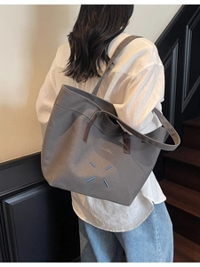 Grey canvas tote bag with signature blue stitching detail and dual shoulder handles