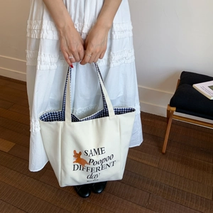 Close-up of canvas tote bag featuring dog print and blue gingham pattern inner lining