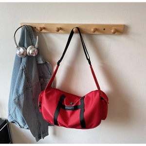 Vista dettagliata di una borsa sportiva in nylon rosso con manici neri su un gancio