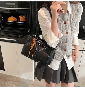 Détail du sac cabas en cuir noir avec surpiqûres blanches et pendentif en cordon orange