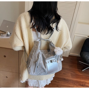 Detail of silver-grey soft leather backpack with plush cloud charm and metal buckle lock