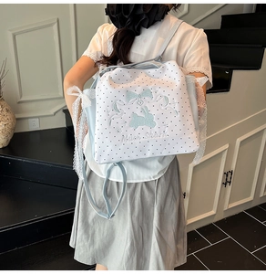 Détail du sac à dos bleu ciel à pois avec broderie lapin et bordures en dentelle blanche