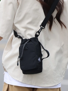 Schwarze Damen-Umhängetasche aus Nylon mit Kordelzug und Reißverschlussfach am Modell