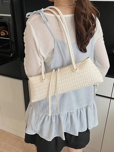 Minimalist cream woven shoulder bag with long tassel detail and cylindrical handle
