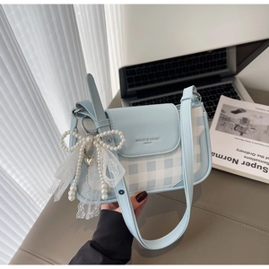 Close-up of light blue plaid handbag with pearl bow lace pendant and leather trim details