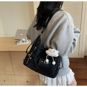Detail of black pleated hobo bag with a white cloud plush charm and side zipper pocket