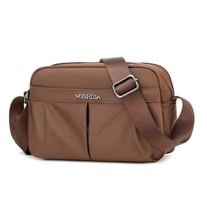 Close-up of brown pleated fabric shoulder bag featuring silver metal logo and wide strap