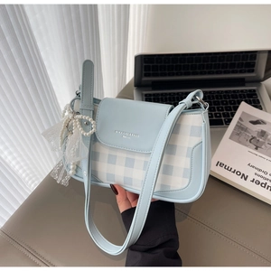 Detail of light blue checkered underarm bag with pearl lace charm and magnetic flap