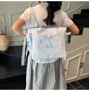 Détail du sac à pois blanc avec broderie lapin bleu et décoration de nœud en dentelle