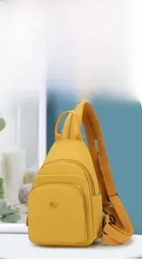 Detailed view of yellow oxford fabric crossbody bag with double zippers and metal logo