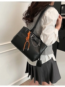 Sac fourre-tout noir avec surpiqûres blanches et chaîne argentée porté par un mannequin