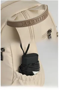 Detail of beige Oxford backpack showing brand leather handle and side pocket with umbrella