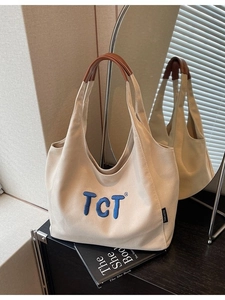 Minimalist cream canvas tote bag with brown leather handles and blue embroidered TCT letters