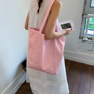 Pink and white gingham canvas tote bag shown on a model in a minimalist interior