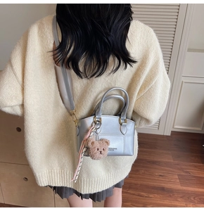 Detail of silver mini bucket bag with plush bear charm and leather texture