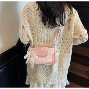 Detail of pink plaid shoulder bag with lace bow pendant and pearl strap on model