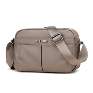 Detail of taupe nylon crossbody bag with dual front pockets and silver metal hardware