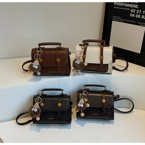 Detailed view of vintage crossbody bags in dark brown, beige and black with furry charms