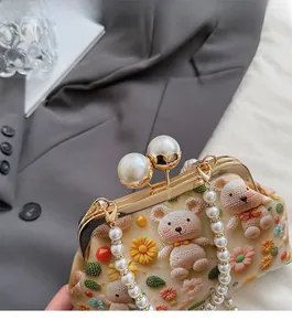 Detail of the golden metal clasp with large pearls and crochet bear on the handbag
