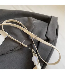 Détail d'une bandoulière crème réglable avec perles de marbre sur le sac à main