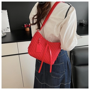 Dettaglio della borsa a tracolla intrecciata rossa con lunghe nappe in pelle e targhetta