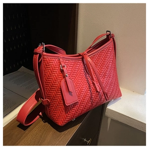 Detail showing red woven texture PU leather handbag with adjustable strap and metal feet