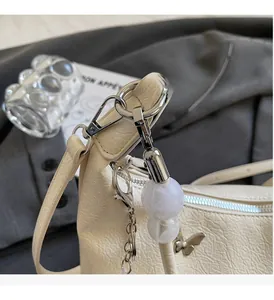 Détail du sac à bandoulière en cuir crème avec breloque papillon argentée et perle marbre