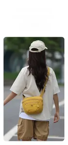 Detail of yellow canvas crossbody bag with multi-zipper layers and adjustable wide strap