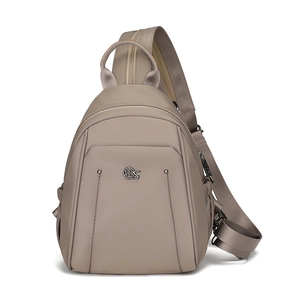 Detail of khaki nylon chest bag showing the circular metal logo and textured fabric