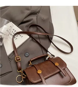 Detail of vintage dark brown handbag showing dual buckles and adjustable shoulder strap