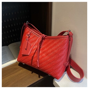 Detailed view of red hand-woven leather bag with metal base studs and decorative tag