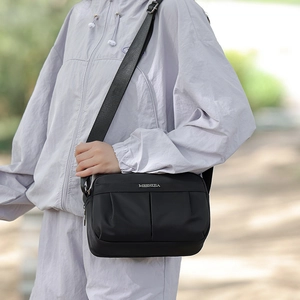 Detail of MSSHIJA black crossbody bag showing pleated nylon fabric and woven strap