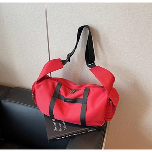 Dettaglio borsa sportiva rossa in tessuto Oxford con cinghie nere posata su libri