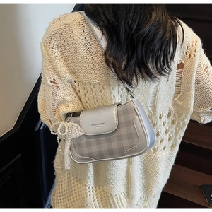 Detail of silver checkered underarm bag with pearl lace charm and textured finish