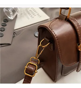 Detail of vintage brown leather handbag with antique gold metal buckle and stitching