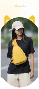 Detail view of a yellow Oxford cloth crossbody bag with dual zippers and adjustable strap