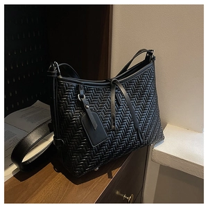 Detail of V-shape woven texture on black tote bag with leather strap and metal studs