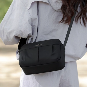 Detailed back view of a black nylon shoulder bag showing crossbody fit on a model