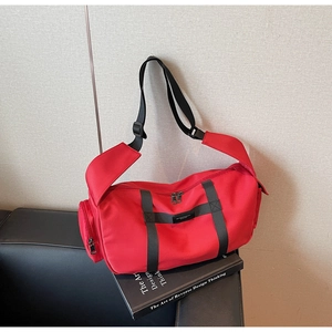 Dettaglio borsa fitness in tessuto oxford rosso con tracolla nera su divano
