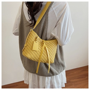 Dettaglio di una borsa tote intrecciata giallo brillante con trama fitta e tracolle