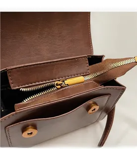 Detail of smooth bronze metal zipper and litchi texture leather on brown handbag