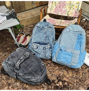 Detailed view of three different vintage wash denim backpacks in an outdoor camping setting