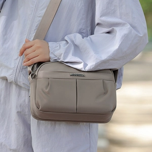 Detail of taupe crossbody bag with vertical pleated texture and metal logo plaque