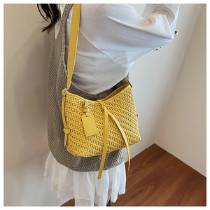 Dettaglio della trama intrecciata gialla e tracolla in pelle di una borsa a spalla